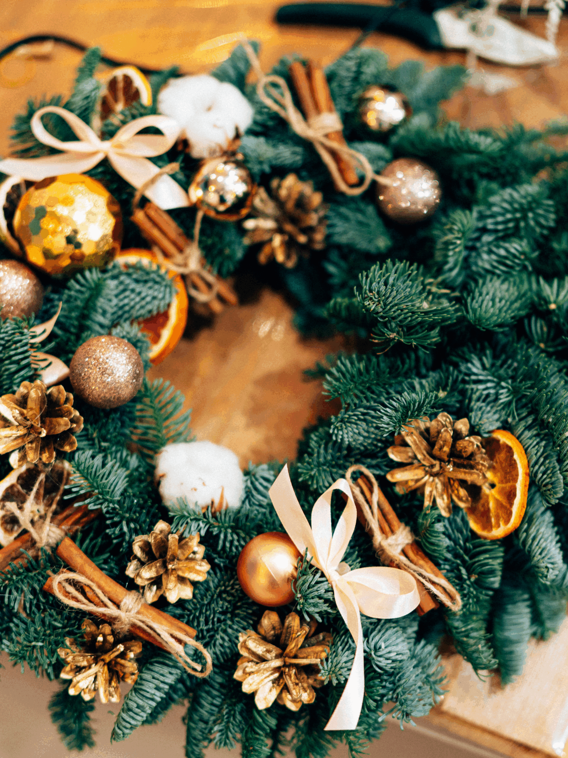 Adventskranz aus Tannenzweigen mit goldenen Zapfen, Zimtstangen, Weihnachtskugeln, getrockneten Orangenscheiben und Schleifen als Beispiel für einen DIY Adventskranz Workshop in Hannover bei Skapa Studio – Weihnachtsdeko selber machen und Adventskranz gestalten.